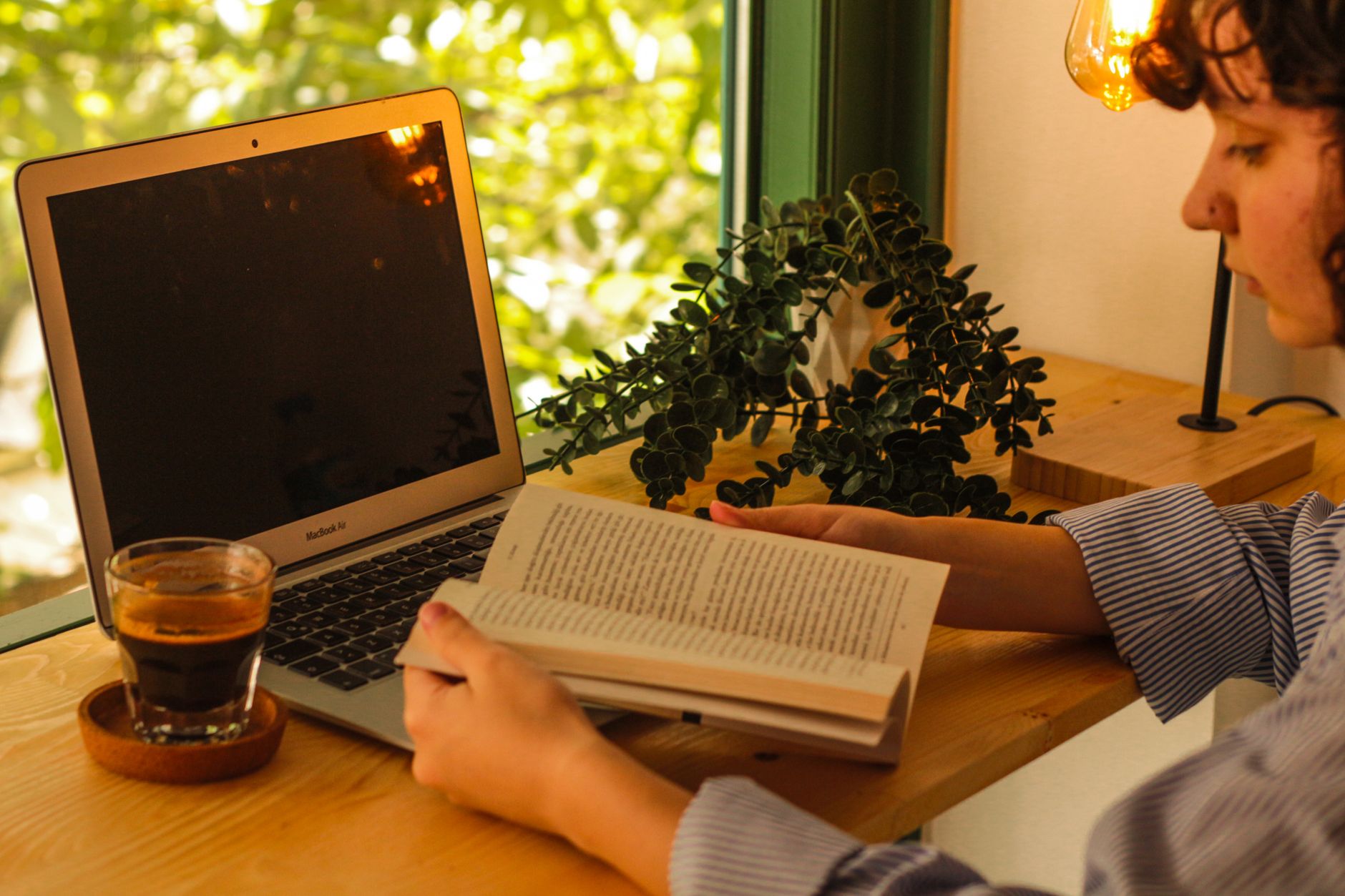 Warme Innenraum-Szene mit Laptop, Kaffee und Buch als gemütlicher Arbeitsplatz.